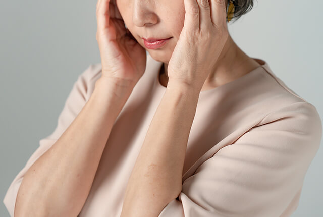 頭を押さえている高齢女性
